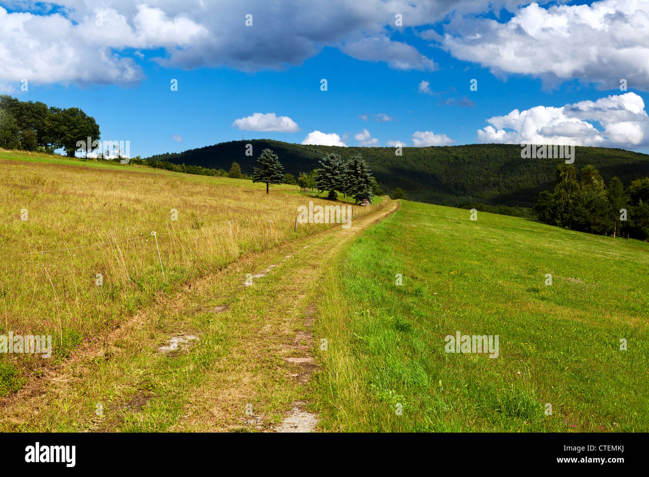 rural road under blue sky in wild mountains Stock Photo