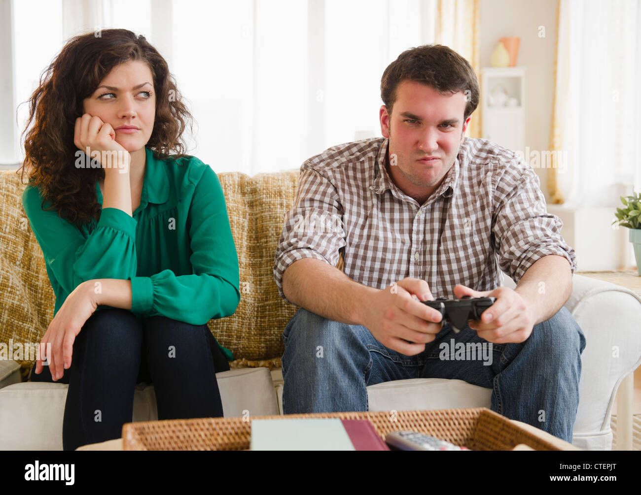 USA, New Jersey, Jersey City, Couple sitting on sofa, man playing video game Stock Photo