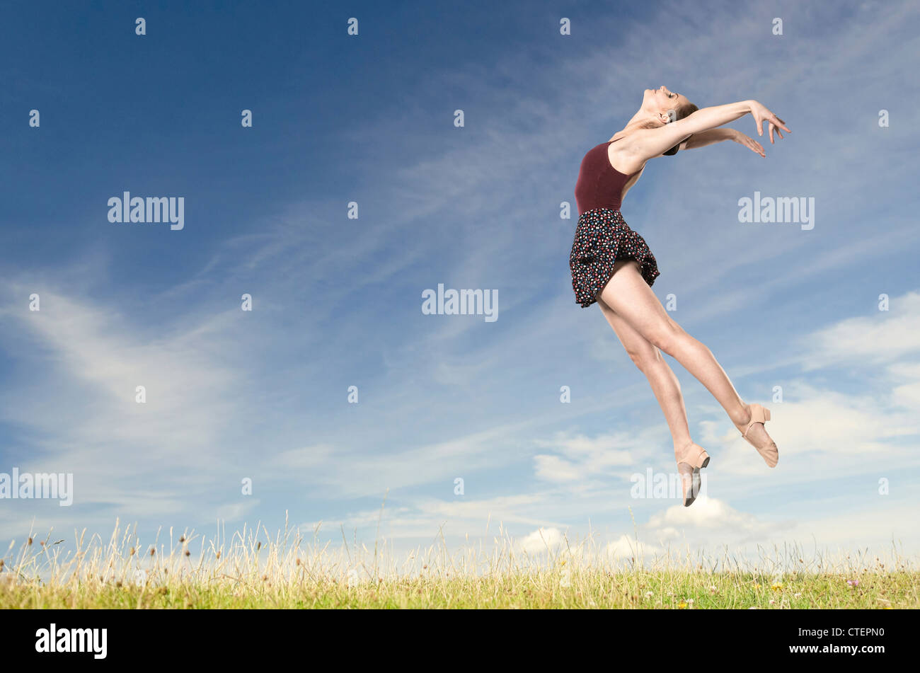 Jumping young woman in front of blue sky Stock Photo - Alamy