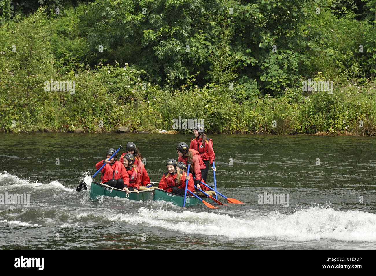Two full canoes bound together rocking in wake of dinghy passing close to them on Gorton Lower