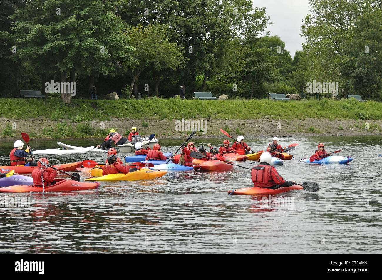 Group of canoes paddled by young children with instructor keeping watch