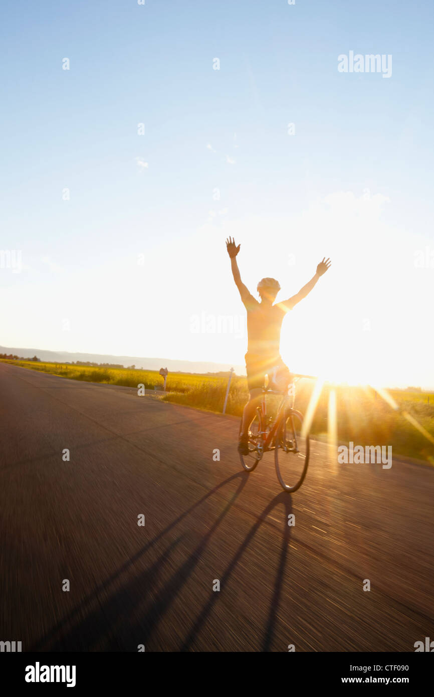USA, Montana, Kalispell, Silhouette of cyclist holding arms up Stock Photo