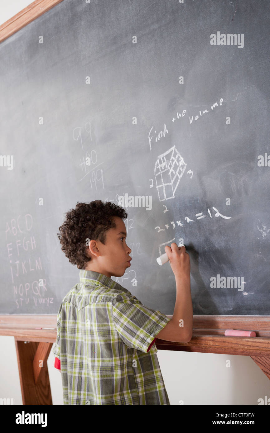 USA, California, Los Angeles, Schoolboy writing on blackboard Stock Photo