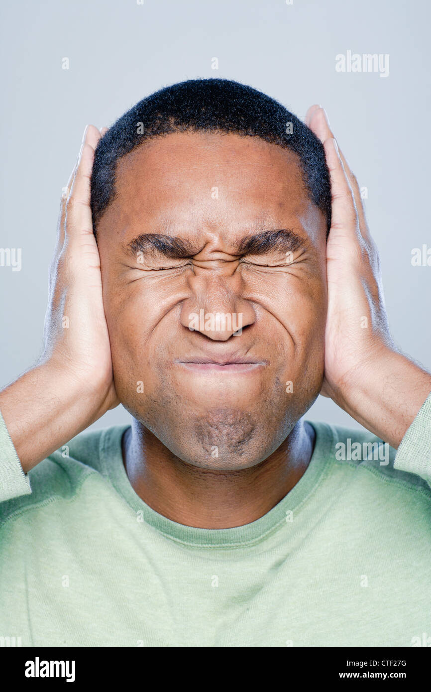 Young man with hands covering ears, studio shot Stock Photo Alamy