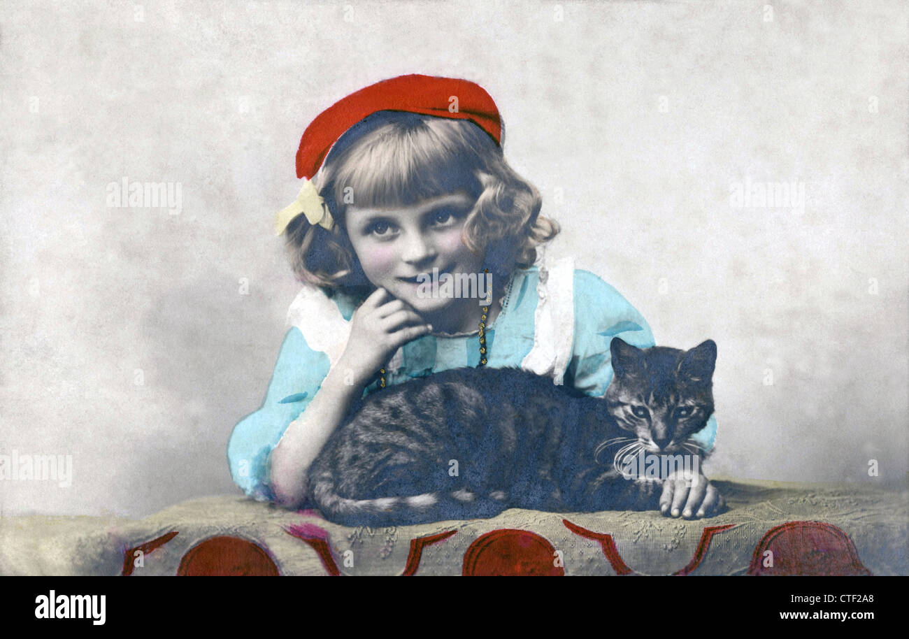 Young girl wearing a red beret with her cat, 1906, vintage photo postcard. Stock Photo