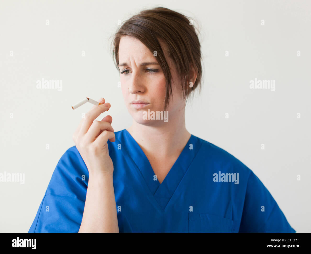 Young woman examining broke cigarette Stock Photo