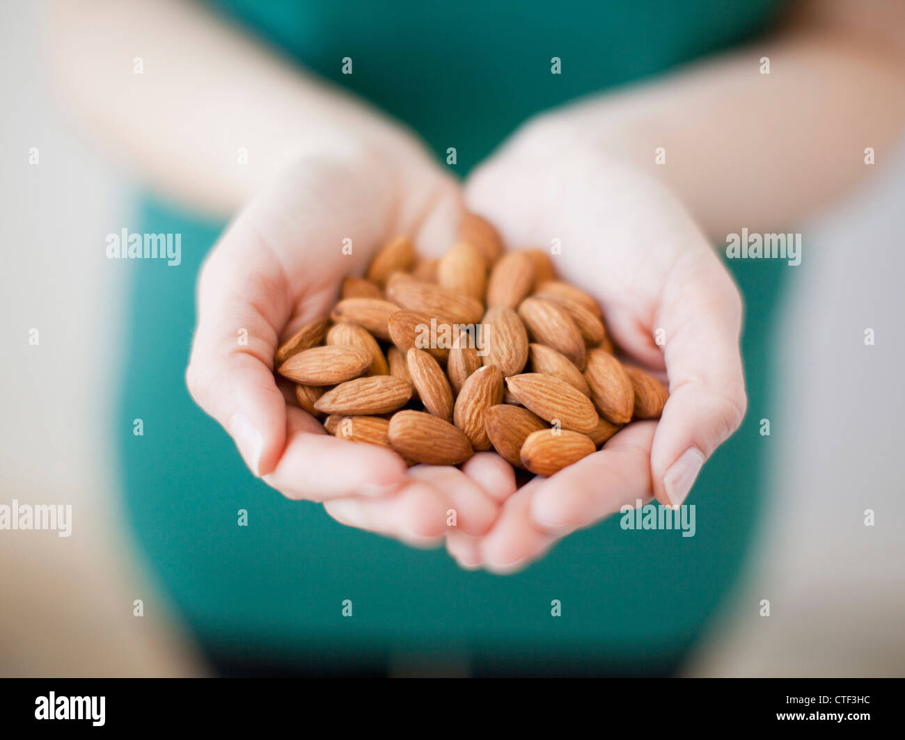 Studio shot of woman showing handful of almonds Stock Photo