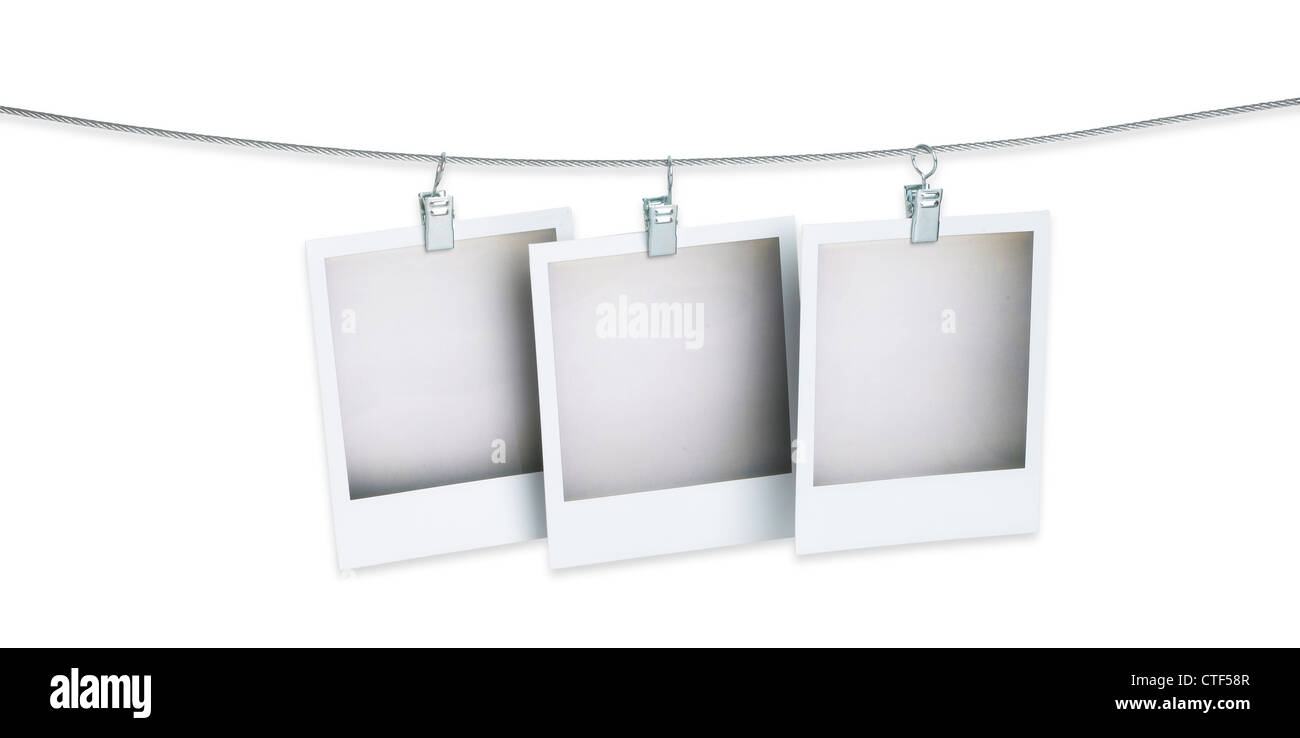 three blank polaroid pictures hanging on a wire isolated on white with clipping path and copy space Stock Photo
