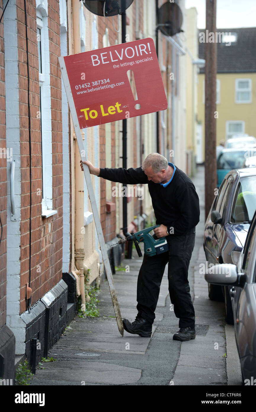 A workman from a letting agency fixes a 'To Let' sign to a property in Gloucester UK Stock Photo