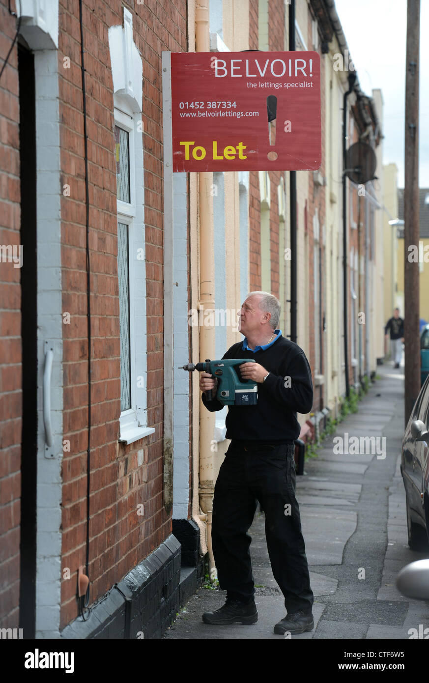 A workman from a letting agency fixes a 'To Let' sign to a property in Gloucester UK Stock Photo