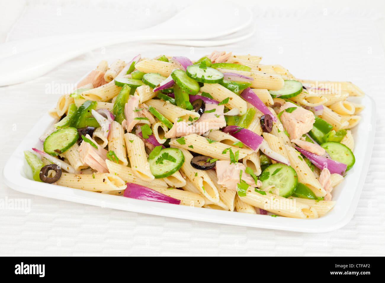 A pasta salad with a basil pesto dressing, tuna, olives, red onion
