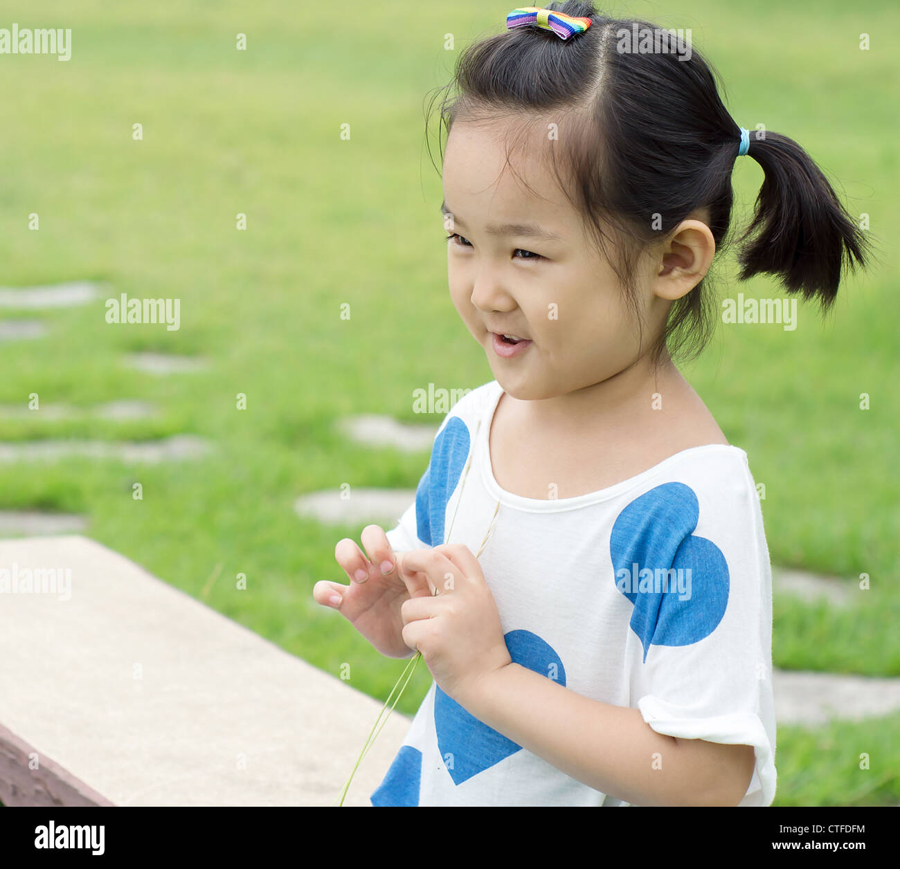 Happy little girl sitting on a park bench Stock Photo - Alamy