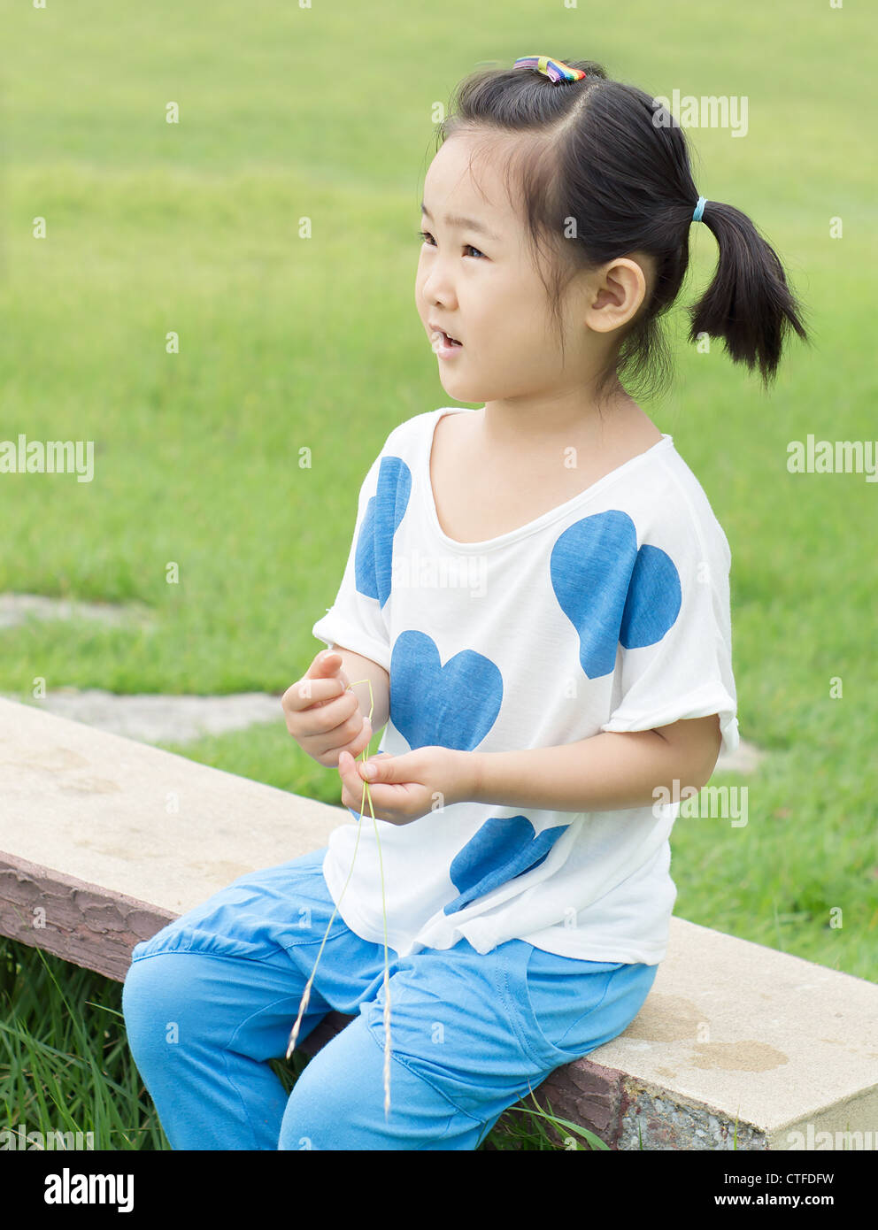 Happy little girl sitting on a park bench Stock Photo - Alamy