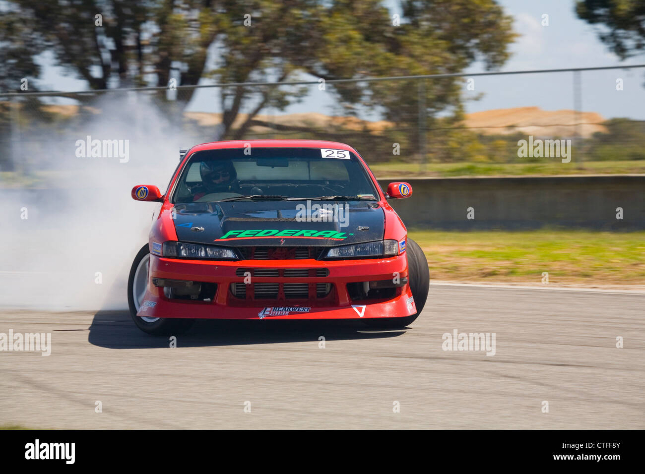 A drift motorsport car sliding sideways with tire smoke into a corner during a drifting competition. Stock Photo