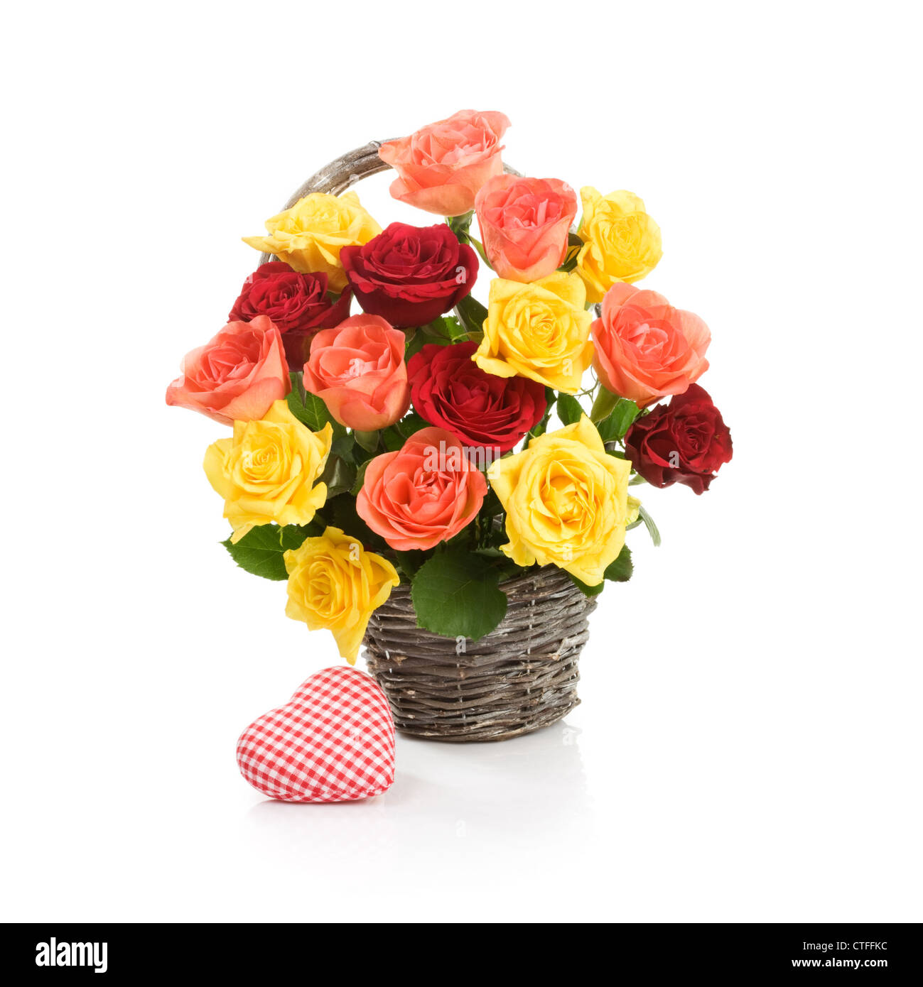 Basket with fresh colorful roses and fabric heart on white background Stock Photo