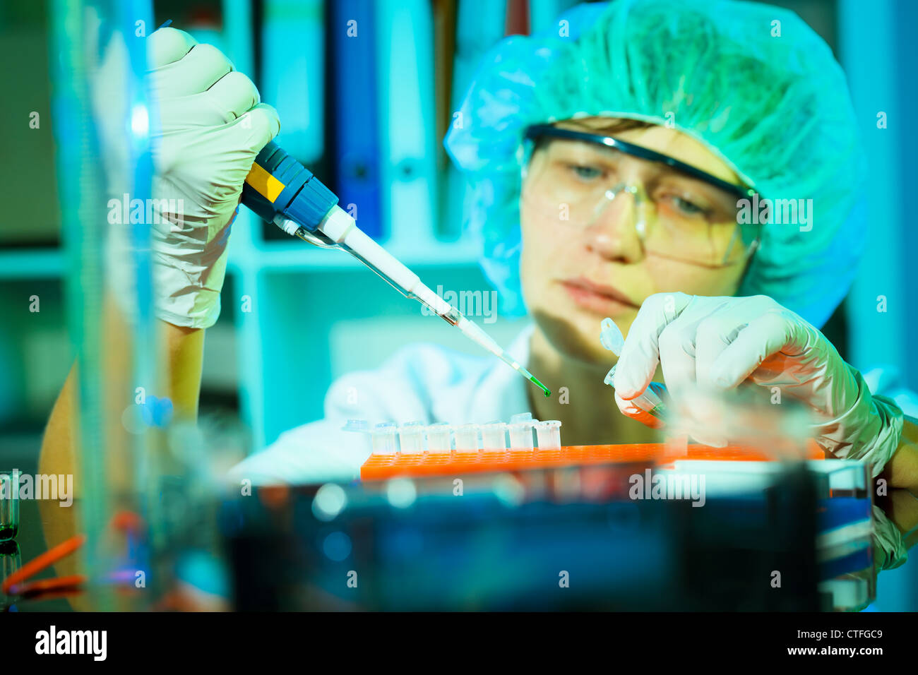 Researcher uses a pipette to infect a culture of human cells with a virus. Stock Photo