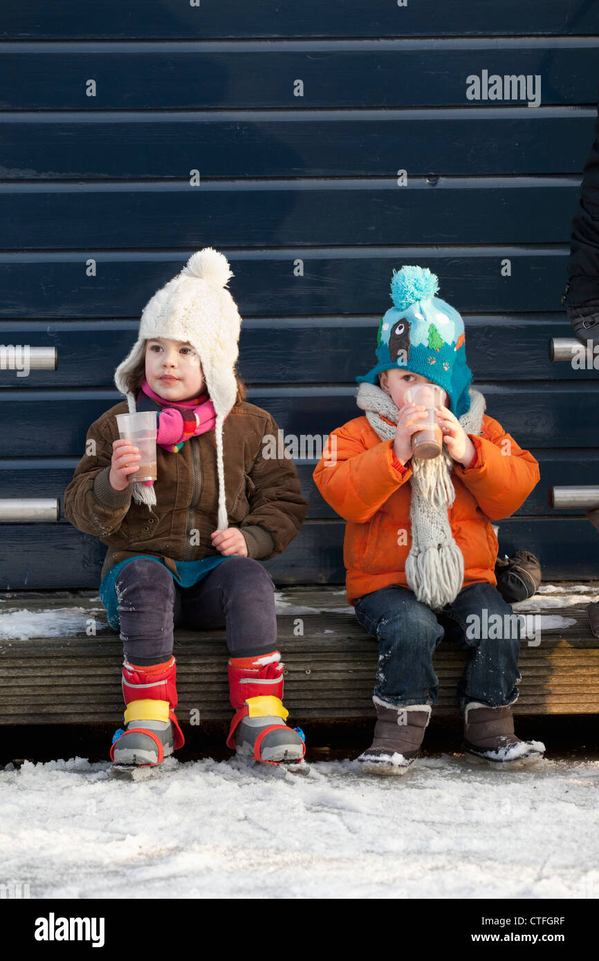 The Netherlands, Amsterdam, Winter, ice skating on frozen canals. Keizersgracht. Two children having a warm drink. Stock Photo