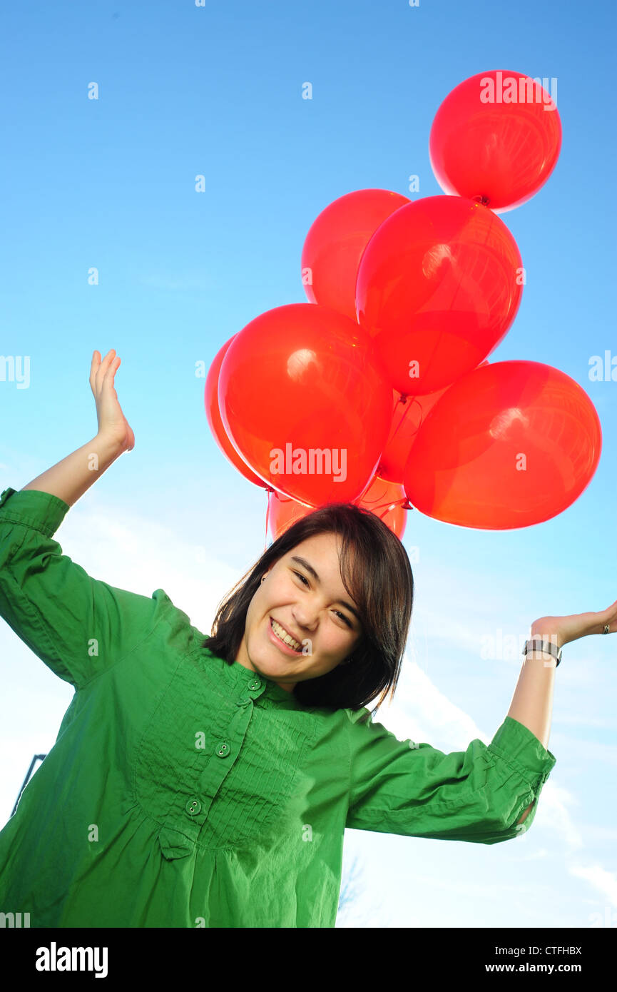 Asian American teenager girl happy holding red balloons Stock Photo - Alamy