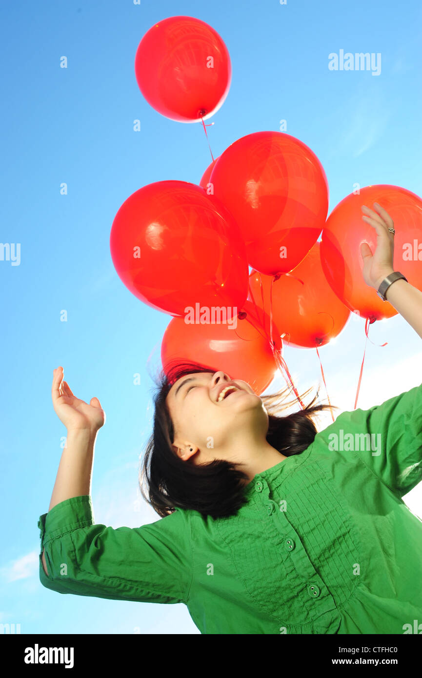 Asian American teenager girl happy holding red balloons Stock Photo - Alamy