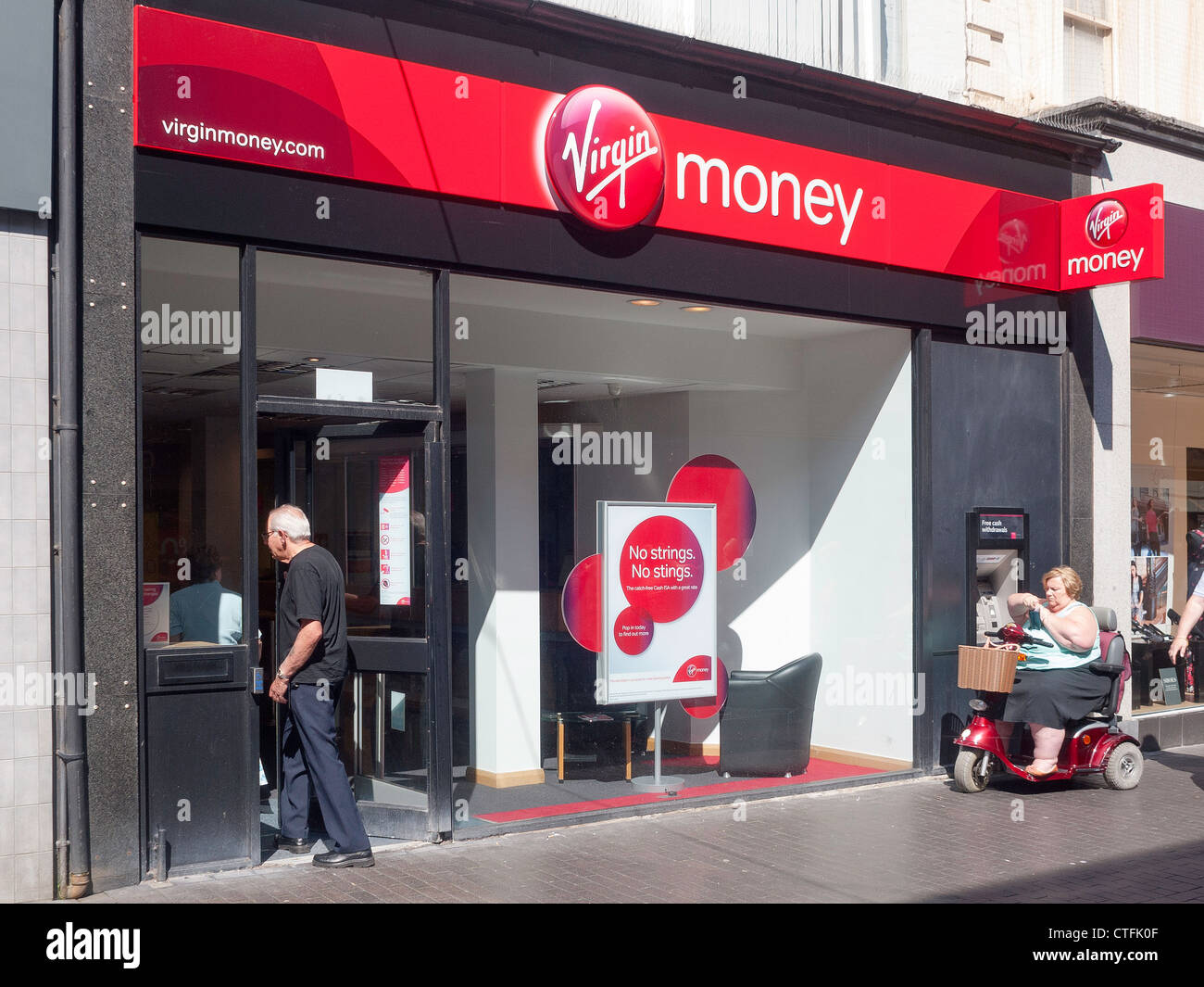 A branch of Virgin Money bank, formerly Northern Rock, in Middlesbrough Cleveland UK with a disabled woman using the cash ATM Stock Photo