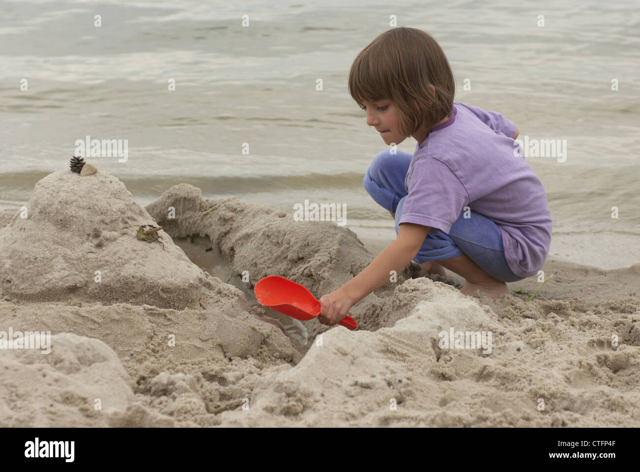Child Girl (5-7 years old) making a sandcastle on the beach Stock Photo