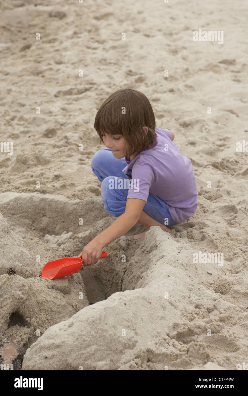 Child Girl (5-7 years old) making a sandcastle on the beach Stock Photo