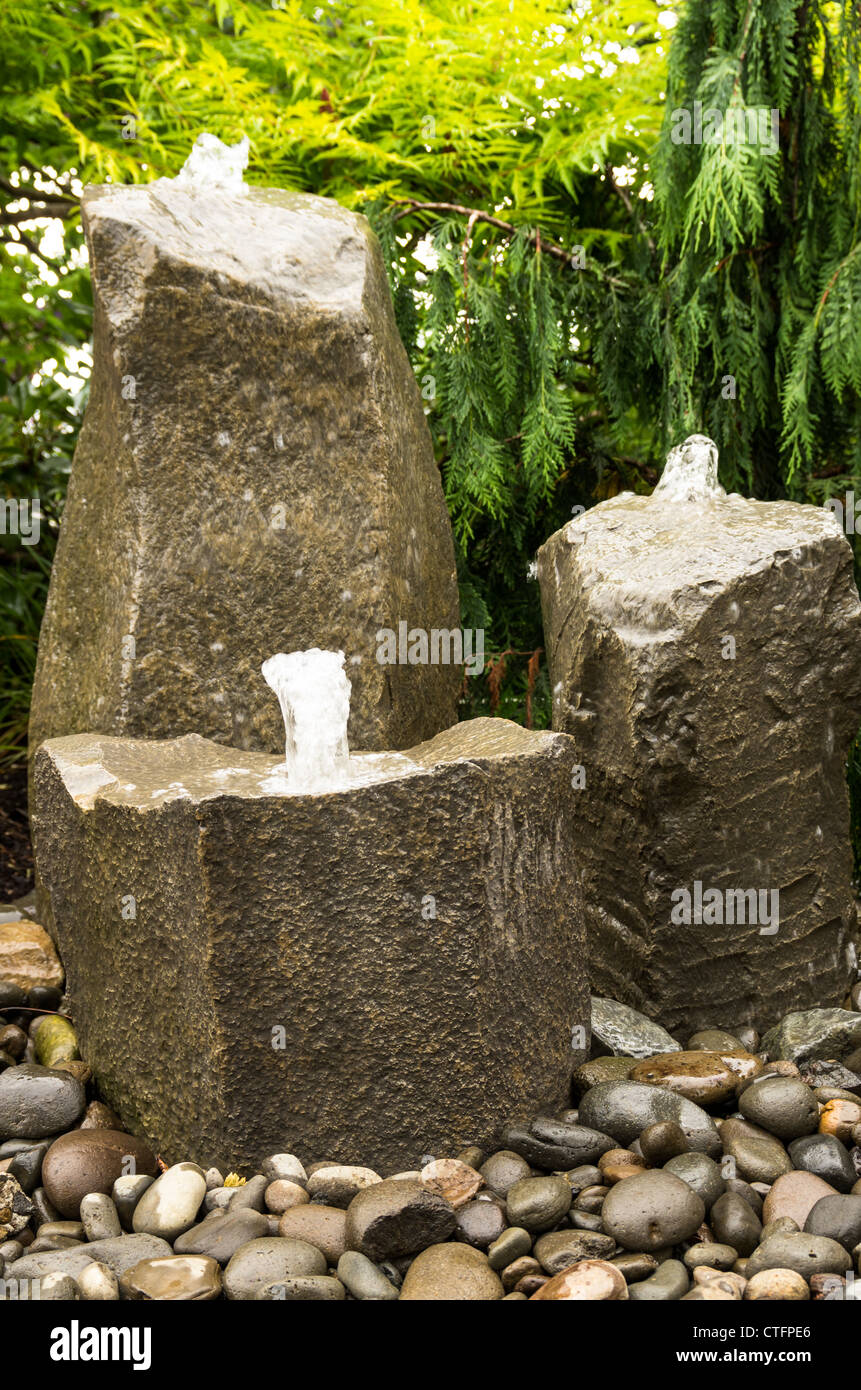 Three rock fountains bubbling water in a garden Stock Photo