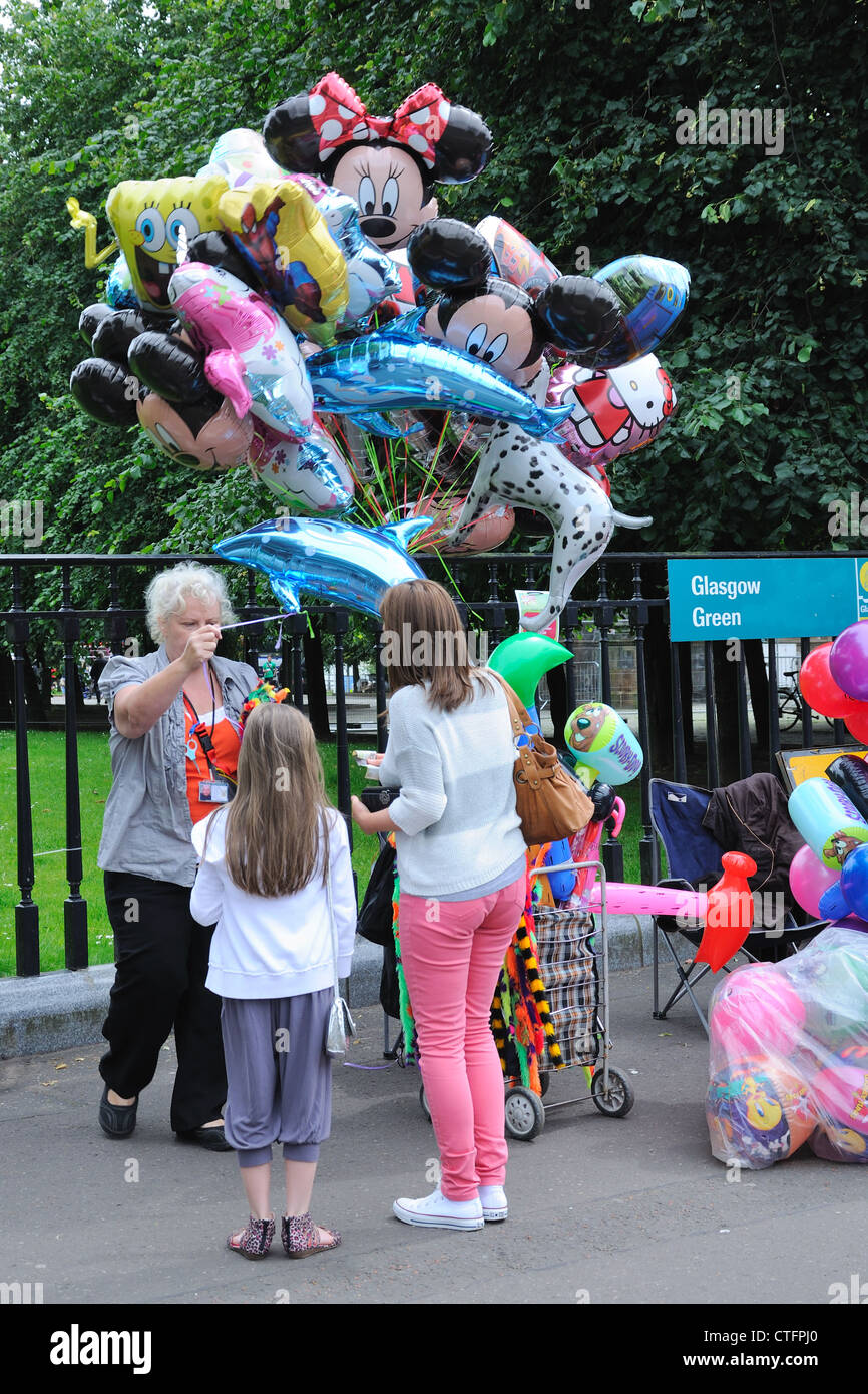 Young girl with mother buying a helium balloon from vendor at the Glasgow Show, Glasgow Green