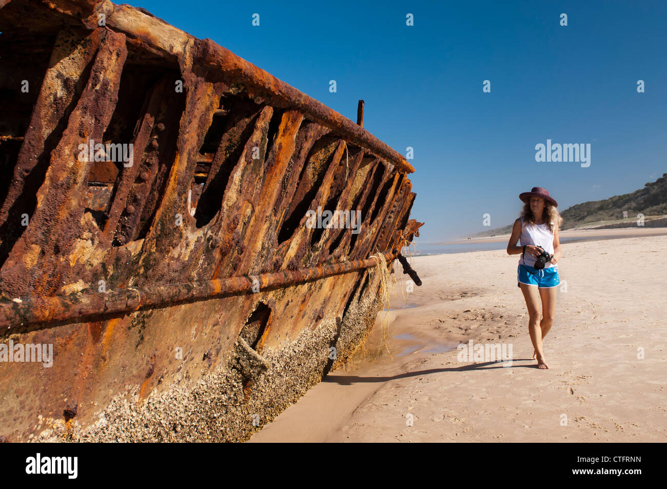 Woman walking past the Maheno wreck on Fraser Island. Stock Photo