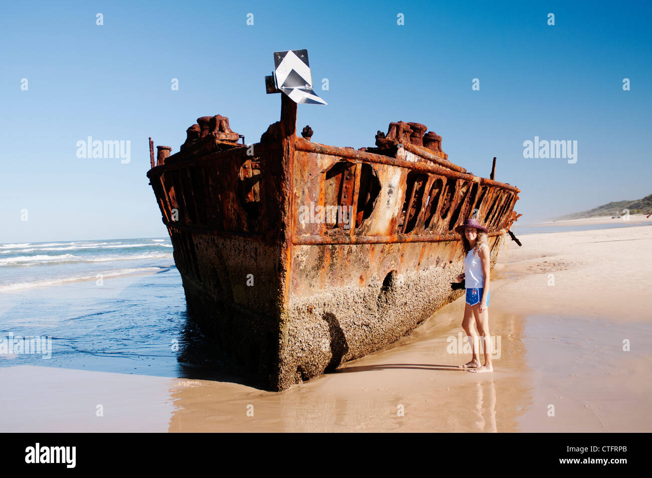Woman on Seventy Five Mile Beach beside the Maheno Wreck. Stock Photo