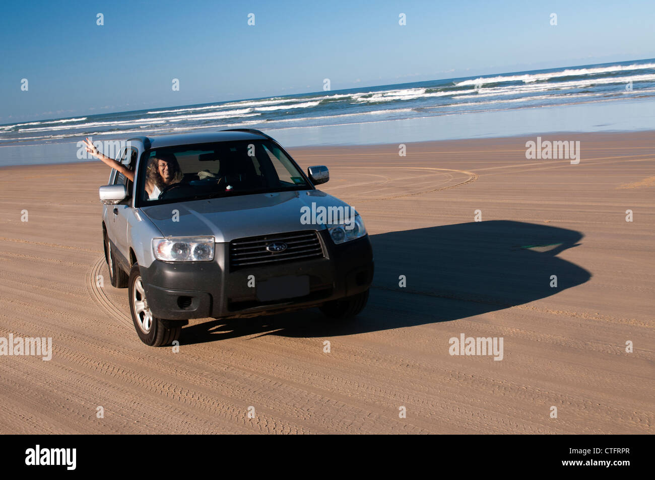 Woman driving four wheel drive car on Seventy Five Mile Beach on Fraser Island. Stock Photo