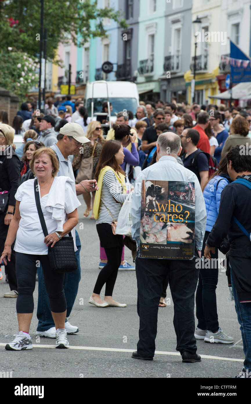 Farm Animal rights campaigner standing with a 'who cares' placard in Portobello Road market. London Stock Photo