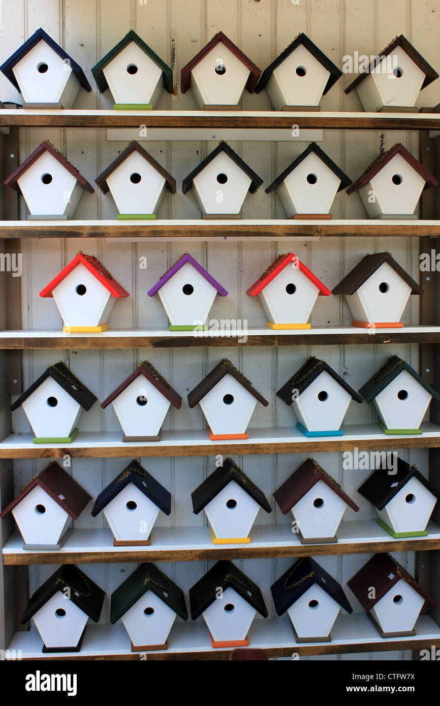 Simple wood shelving unit displaying several hand crafted birdhouses in a variety of colors for bird lovers to choose from. Stock Photo