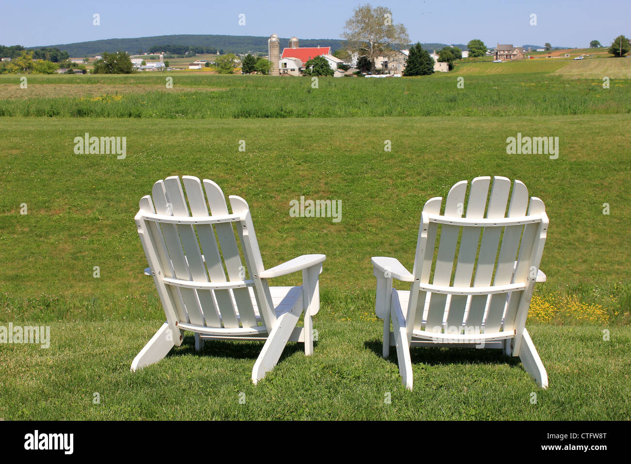 Adirondack chairs on edge of lush green field of countryside farm Stock Photo Alamy