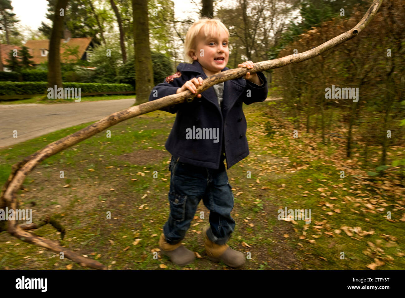 little boy walking with a tree branch in his hands Stock Photo - Alamy