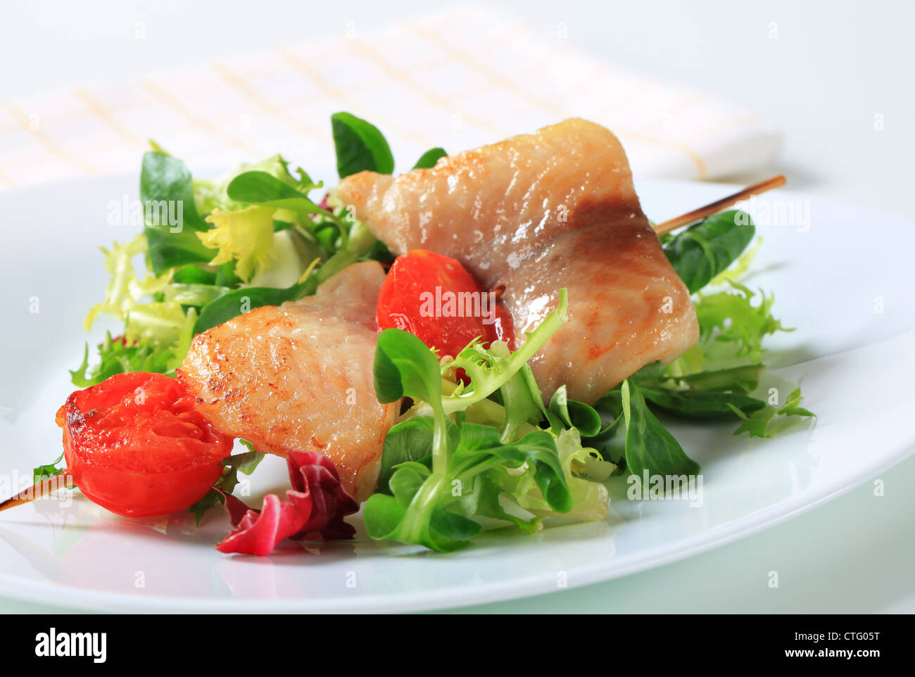 Fish skewer on a nest of salad greens Stock Photo