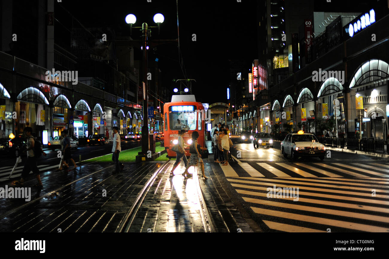 Pedestrians walk in front of a tram in Kagoshima, Japan Stock Photo