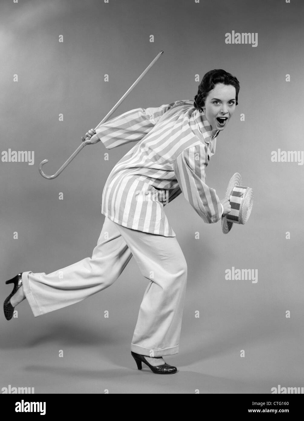 1950s WOMAN IN STRIPED JACKET HOLDING CANE & STRAW HAT SHUFFLING