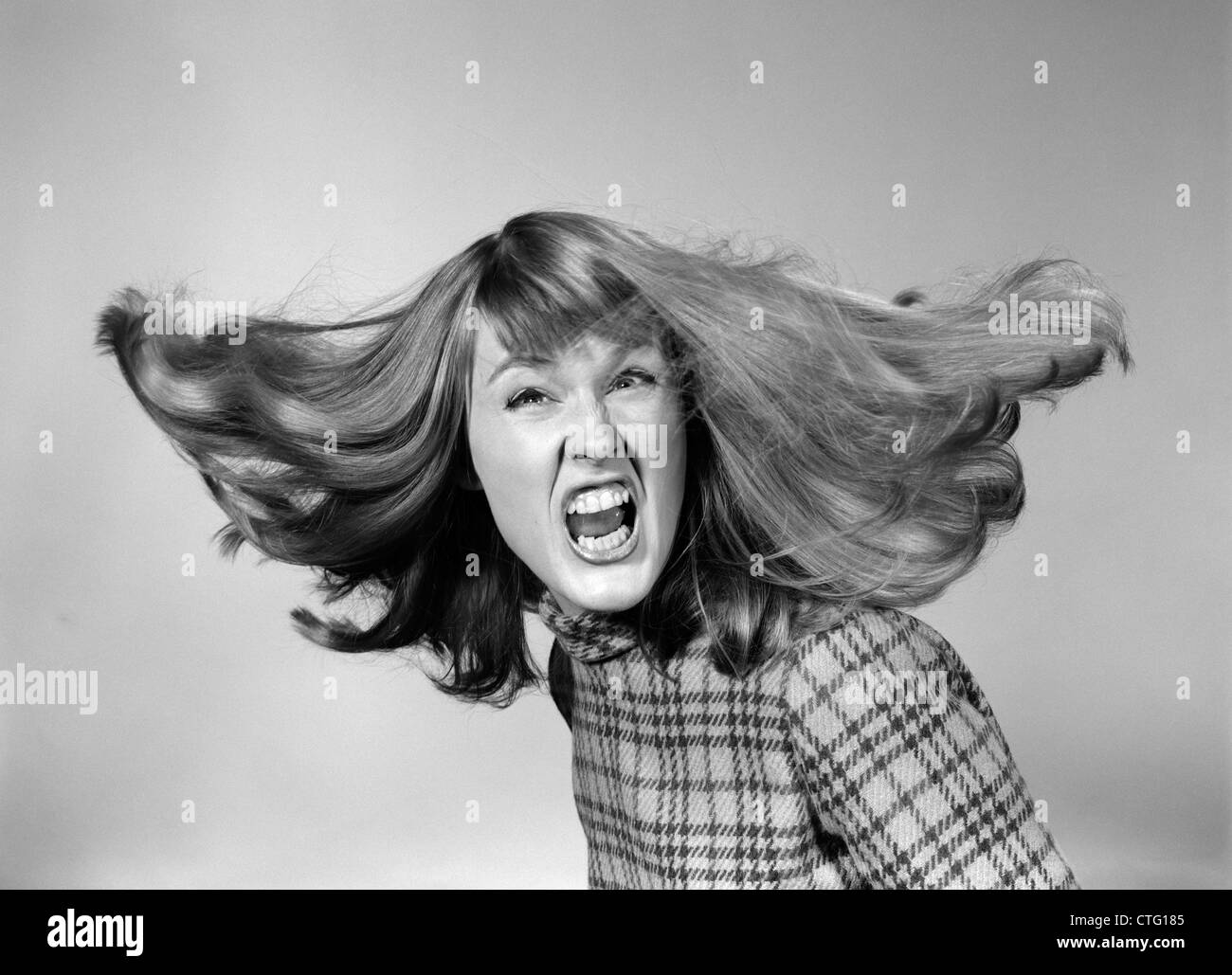 1960s ANGRY WOMAN YELLING GNASHING TEETH HAIR FLYING LOOKING AT CAMERA Stock Photo