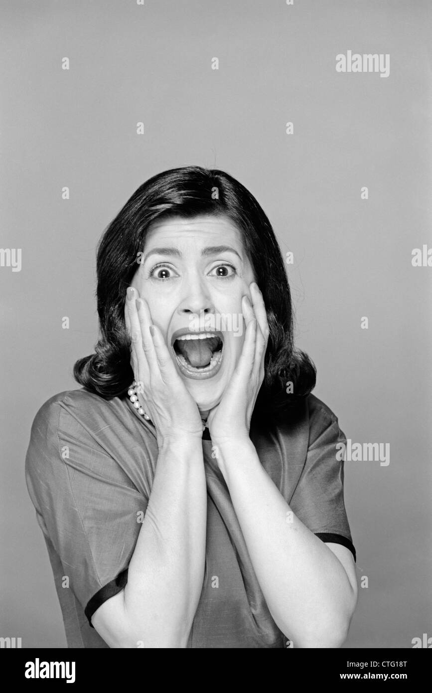 1960s BRUNETTE WOMAN SCREAMING MOUTH WIDE OPEN HANDS TO FACE FACIAL EXPRESSION FEAR SCREAM SURPRISE CHARACTER FUNNY FACE Stock Photo