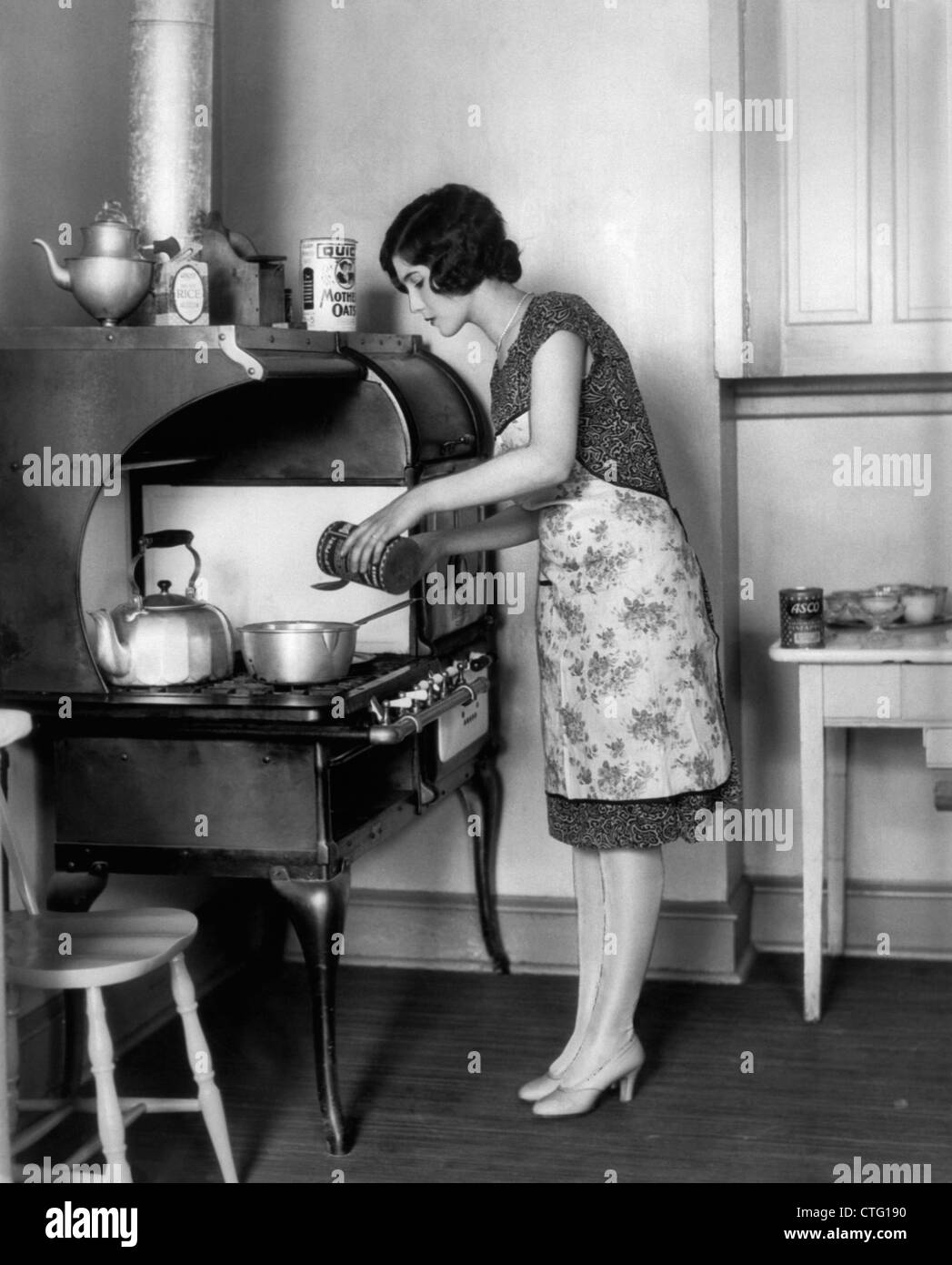 1920s HOUSEWIFE AT STOVE COOKING Stock Photo