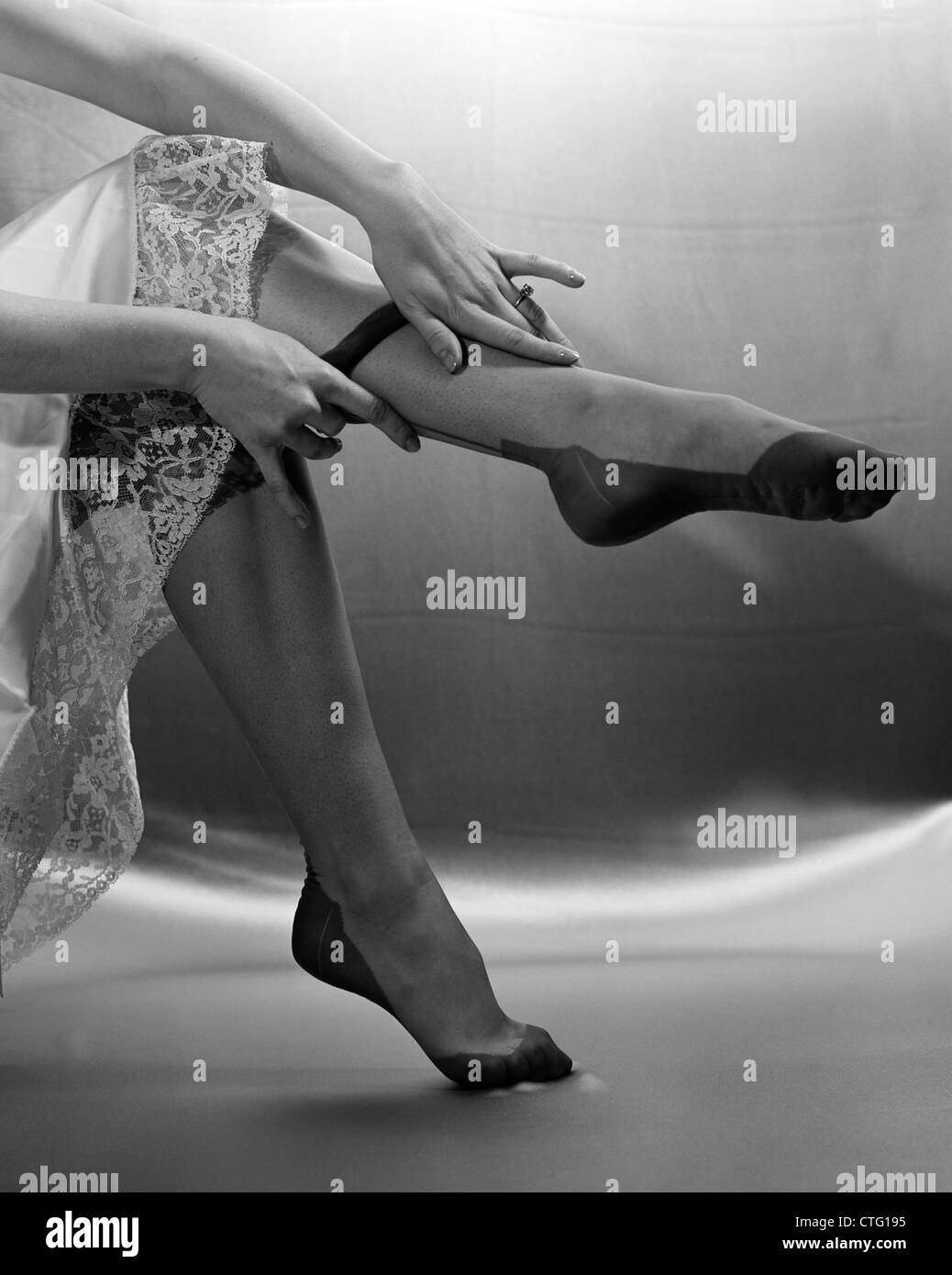 1950s HANDS PULLING ON NYLON HOSIERY WITH THE BOTTOM OF SLIP SHOWING ...