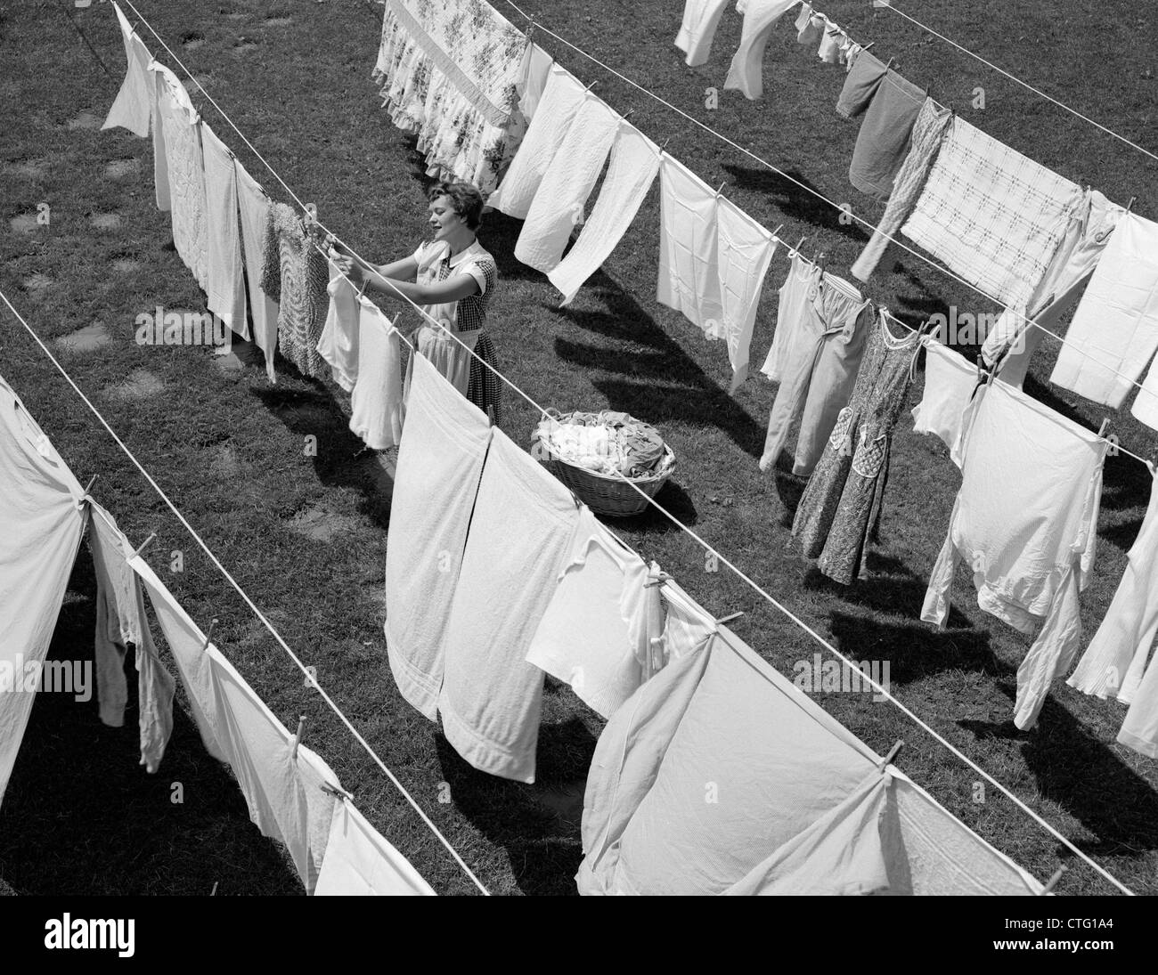 1950s HOUSEWIFE HANGING LAUNDRY IN BACKYARD Stock Photo