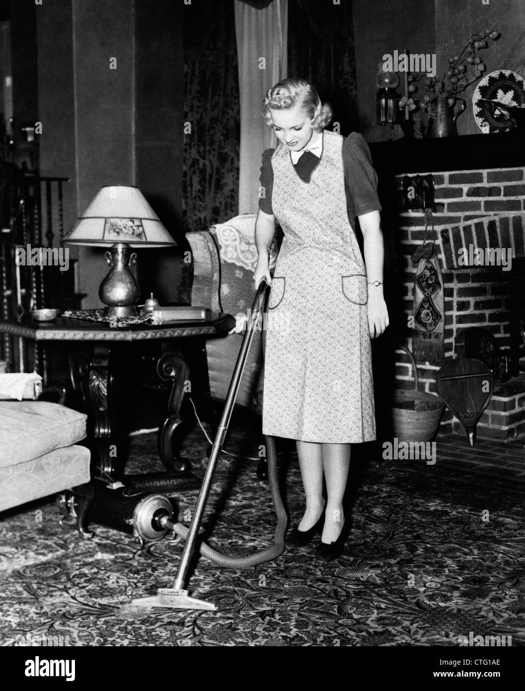 1930s 1940s WOMAN HOUSEWIFE WEARING APRON PUSHING ELECTRIC VACUUM CLEANER  IN ORNATE LIVING ROOM HOUSE CHORE Stock Photo - Alamy
