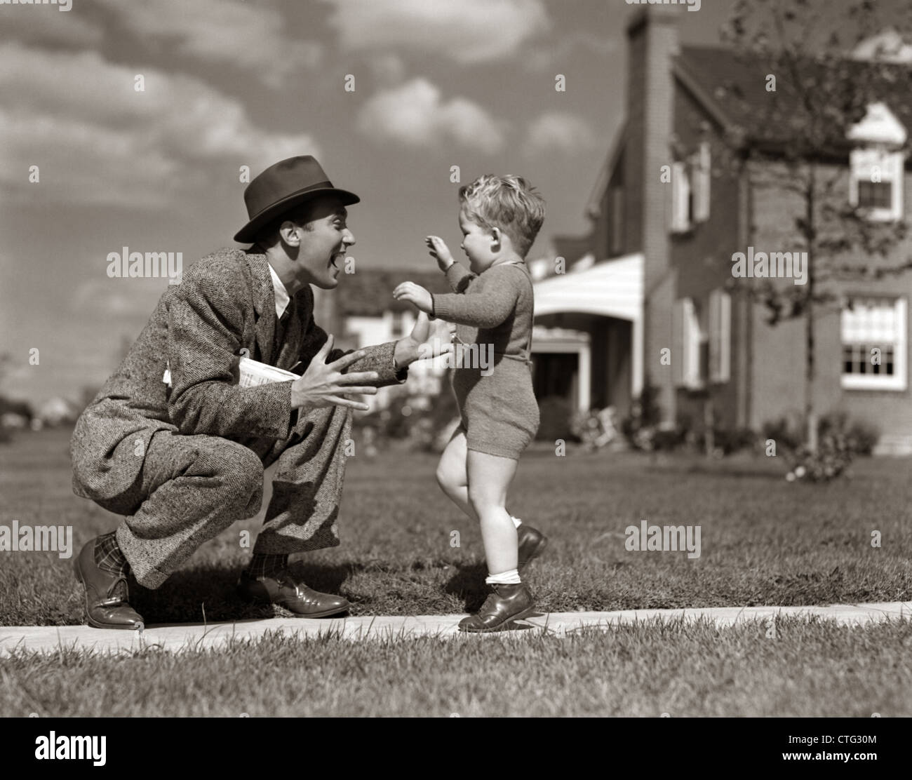 1940s FATHER GREETING SON RUNNING TOWARDS HIM ON SIDEWALK Stock Photo