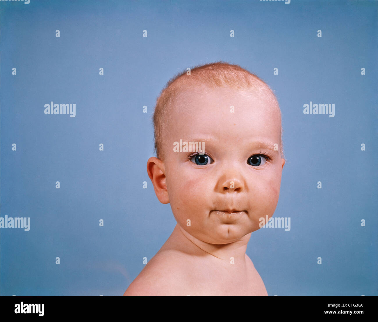 1960s PORTRAIT BABY BLUE BACKGROUND PURSED LIPS FACIAL EXPRESSION Stock