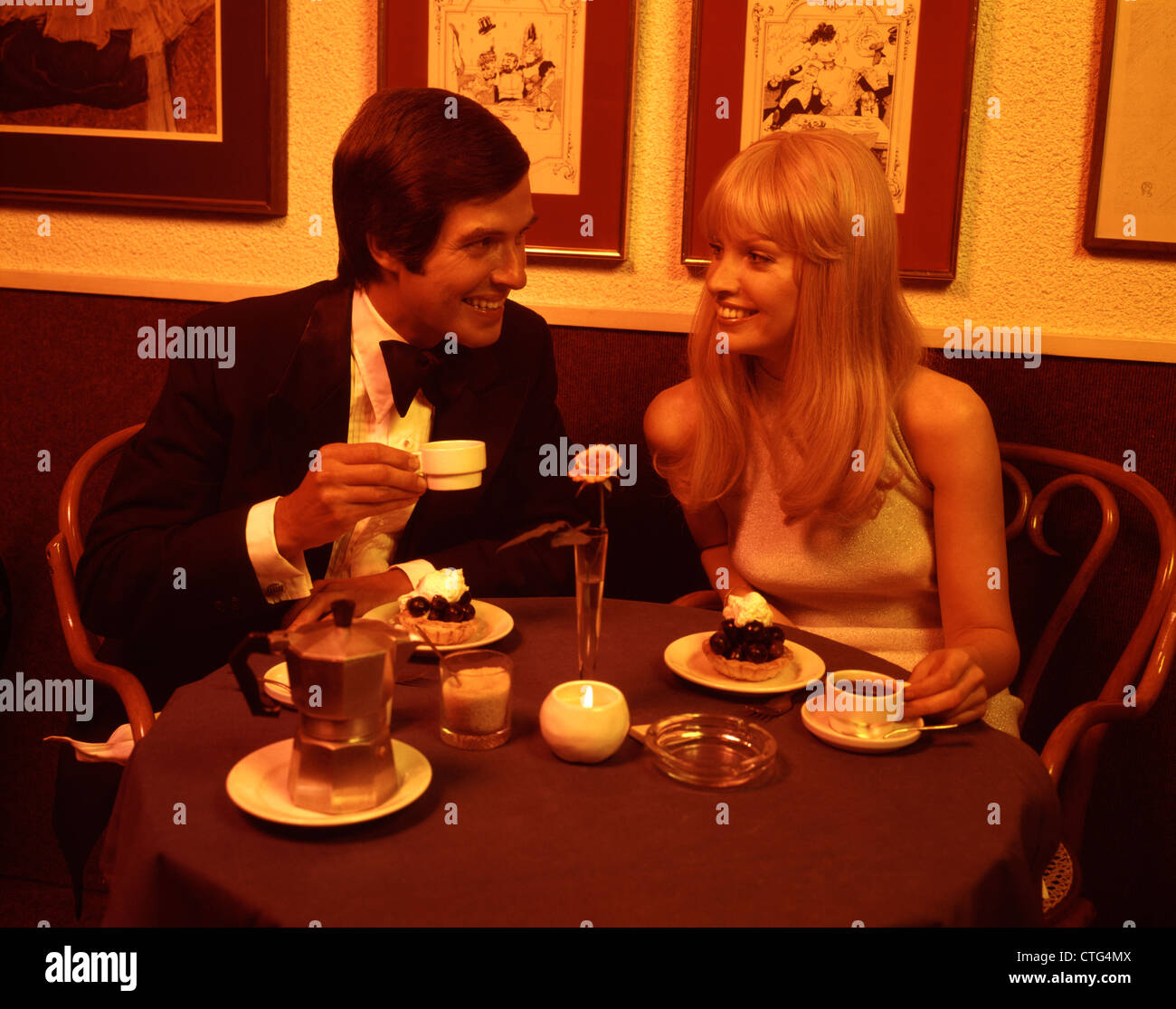 1970s COUPLE DINING ROMANTIC RESTAURANT HAVING DESSERT COFFEE BY CANDLELIGHT Stock Photo