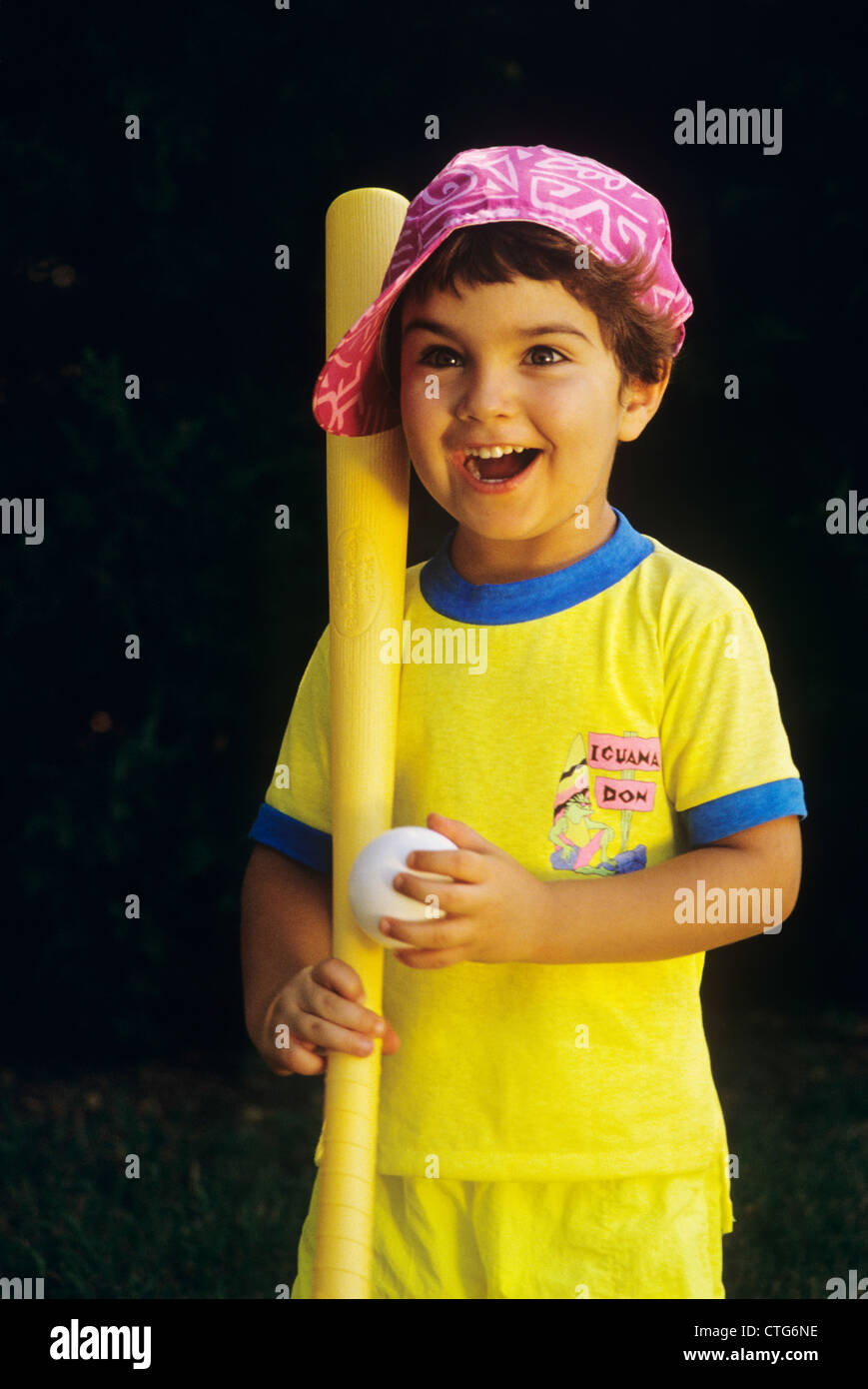 BOY IN PINK HAT HOLDING BALL AND PLASTIC BAT Stock Photo