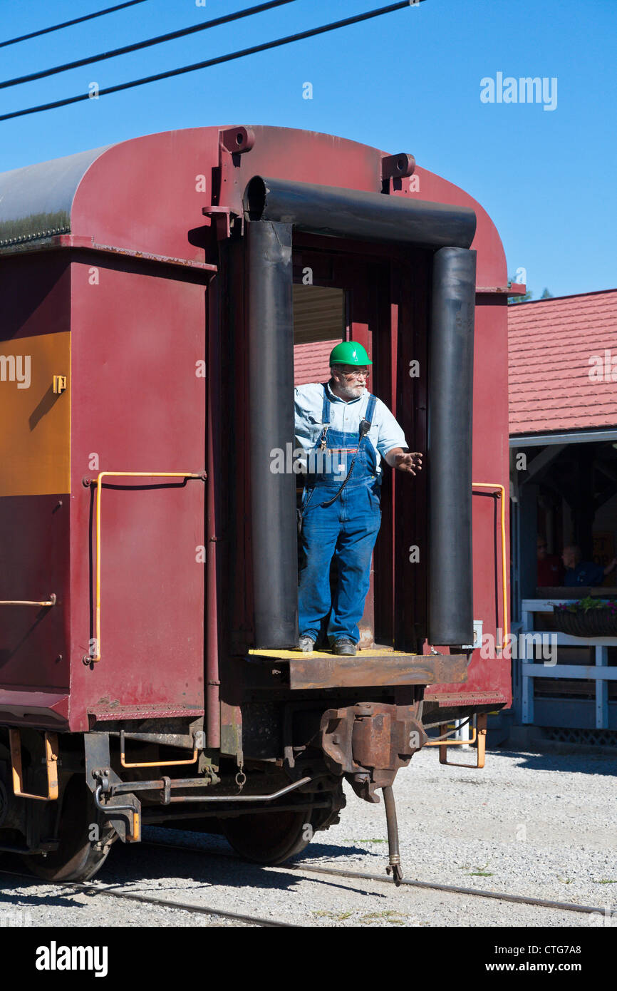 Conductor of Great Smoky Mountain Railway stands in open door at end of passenger car Stock Photo