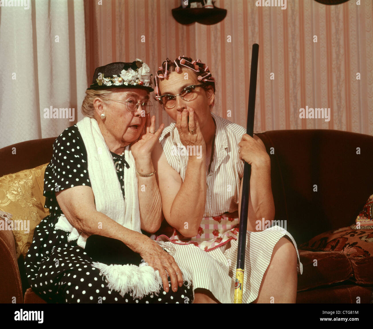 1960s TWO SENIOR OLDER WOMEN SITTING ON SOFA GOSSIPING Stock Photo